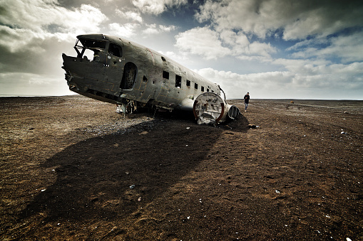Tourist at plane wreck on black sand beach Iceland