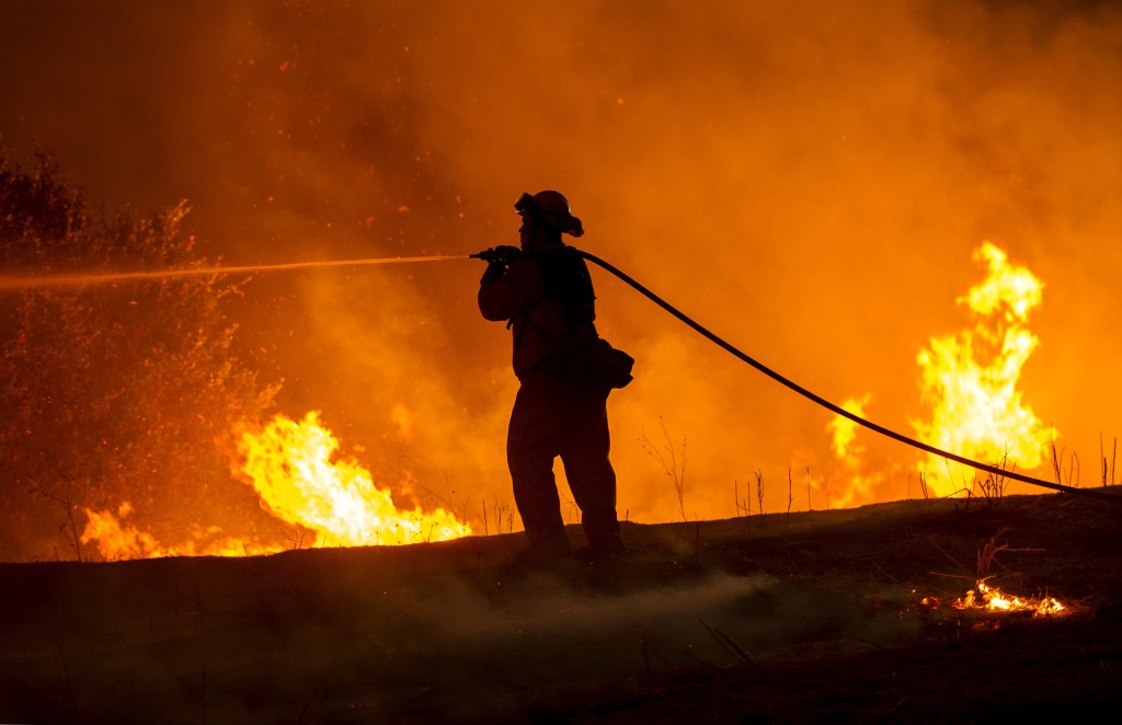 Firefighter Joe Darr douses flames of the Rocky fire along Highway 20 near Clearlake, California on August 2, 2015. Thousands of firefighters battled raging wildfires on August 2 in drought-parched California, where officials evacuated entire neighborhoods and closed miles of highway in the path of the inferno, which has claimed at least one life. AFP PHOTO / JOSH EDELSON        (Photo credit should read Josh Edelson/AFP/Getty Images)