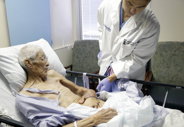 Plastic surgeon Anthony Echo, right, examines Frank Reyes' hand before surgery at Houston Methodist Hospital in Houston on Thursday, Aug. 27, 2015. Reyes, whose hand was badly burned, spent three weeks with his left hand surgically tucked under a pocket of tissue in his belly to give it time to heal and form a new blood supply. (AP Photo/Pat Sullivan)