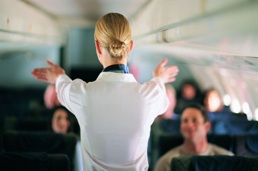 rear-view-of-air-stewardess-explaining-aeroplane-safety-to-passengers-dv776042-576071765f9b58f22ef85596
