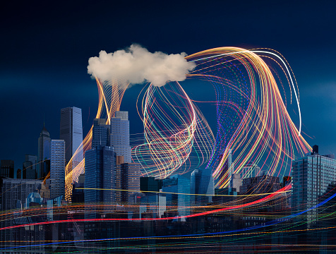 Illuminated light trails and cloud over cityscape