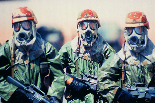 Troop of soldiers in camouflage uniforms, helmets and gas masks