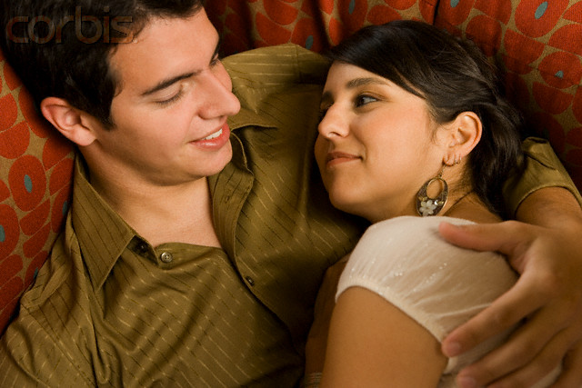 Couple cuddling on couch --- Image by © Steve Hix/Somos Images/Corbis