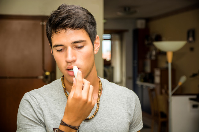 Handsome Young Man Applying Lip Balm at Home