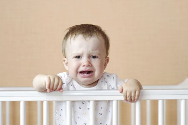 crying baby in white bed