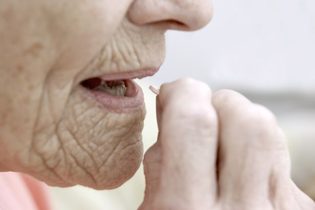 Elderly-woman-taking-a-Simvastatin-tablet-drug