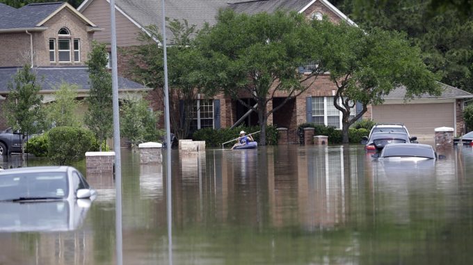 A person paddles through a flooded neighborhood, Tuesday, April 19, 2016, in Spring, Texas. Storms have dumped more than a foot of rain in the Houston area, flooding dozens of neighborhoods. (AP Photo/David J. Phillip)