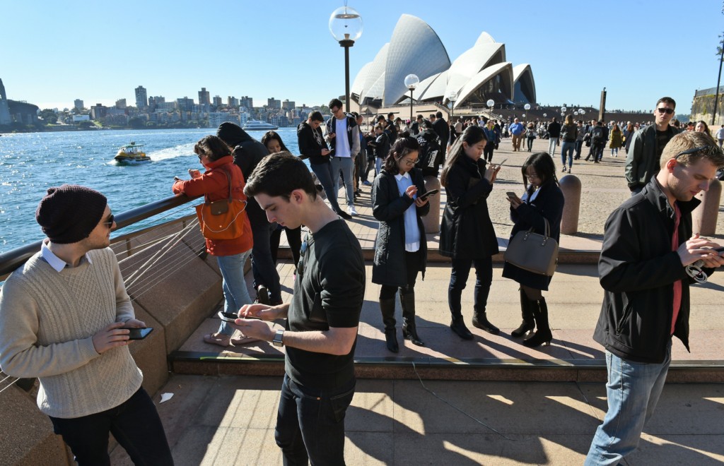 Dozens of people gather to play Pokemon Go in front of the Sydney Opera House on July 15, 2016. The wildly popular mobile app, which is based on a 1990s Nintendo game, has created a global frenzy as players roam the real world looking for cartoon monsters and was launched in Australia last week. / AFP / William WEST        (Photo credit should read WILLIAM WEST/AFP/Getty Images)