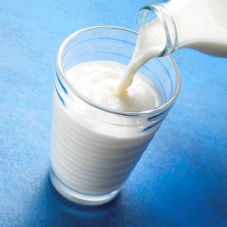 pouring milk into a glass on blue textured background