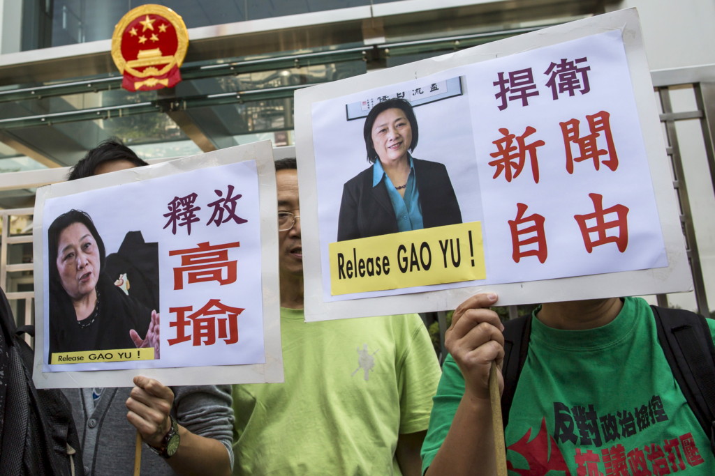 Pro-democracy protesters hold up signs during a demonstration calling for the release of Chinese journalist Gao Yu outside the Chinese liaison office in Hong Kong